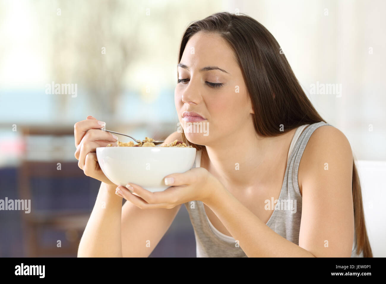 Disgusted woman eating cereals with bad taste at home Stock Photo