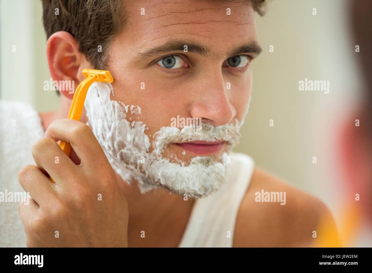 Reflection of young man shaving Stock Photo Alamy