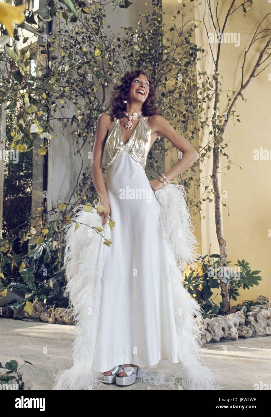 American model Marisa Berenson, posing in a white and gold dress designed by Loris Azzaro.  October 1973 Photo Michael Holtz Stock Photo