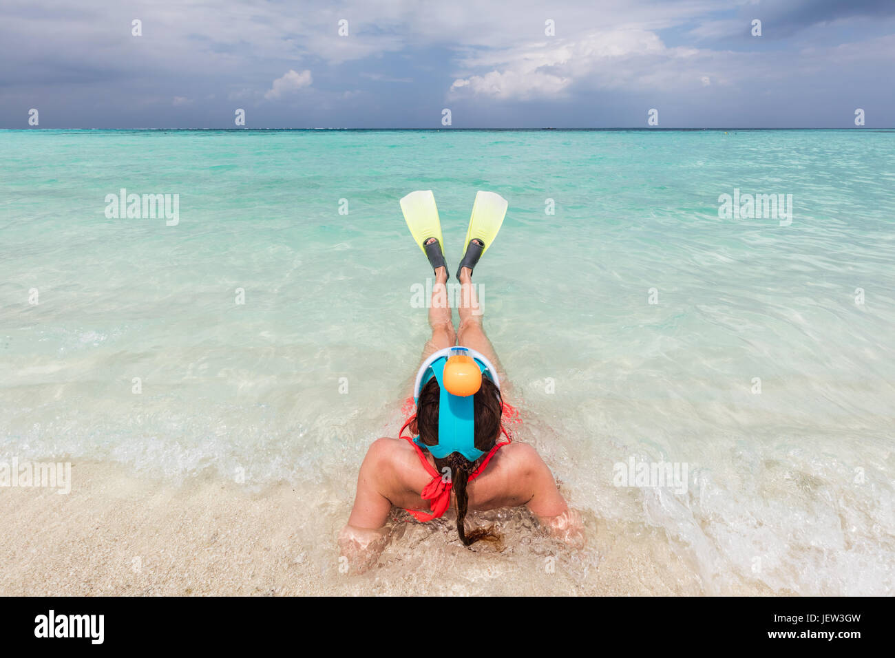 Woman wearing snorkeling mask and fins ready to snorkel in the ocean, Maldives. Clear turquoise water. Stock Photo