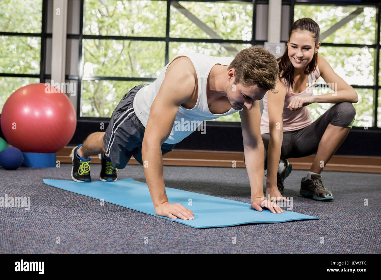 Trainer assisting man with push ups Stock Photo