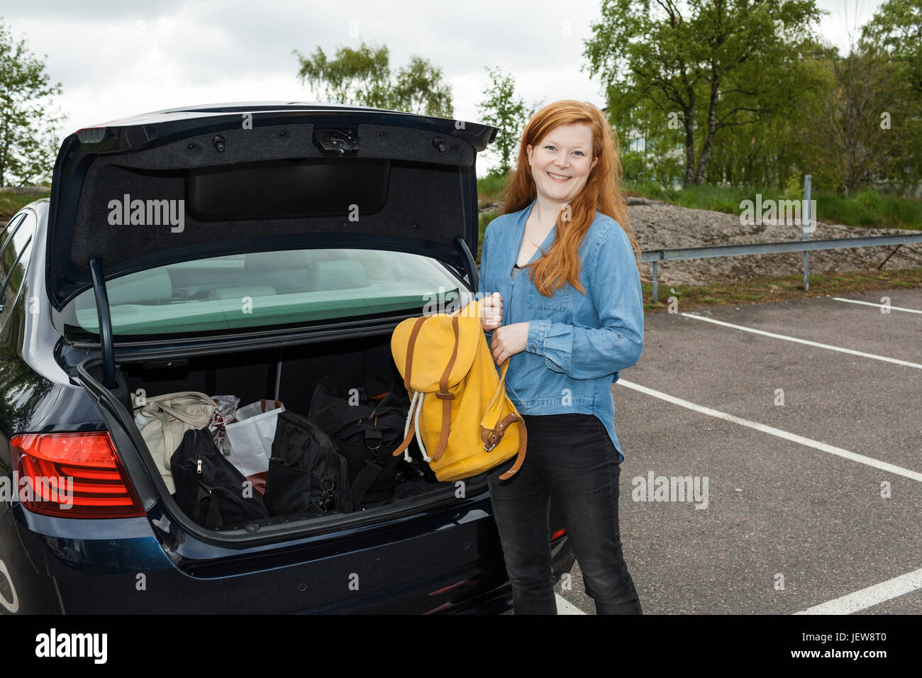 Woman putting backpack in car boot Stock Photo Alamy