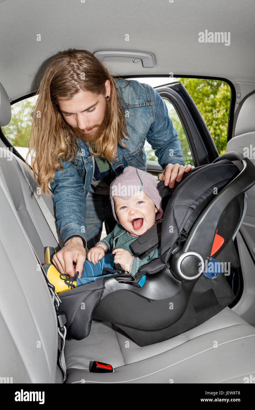 Father putting baby in car seat Stock Photo Alamy