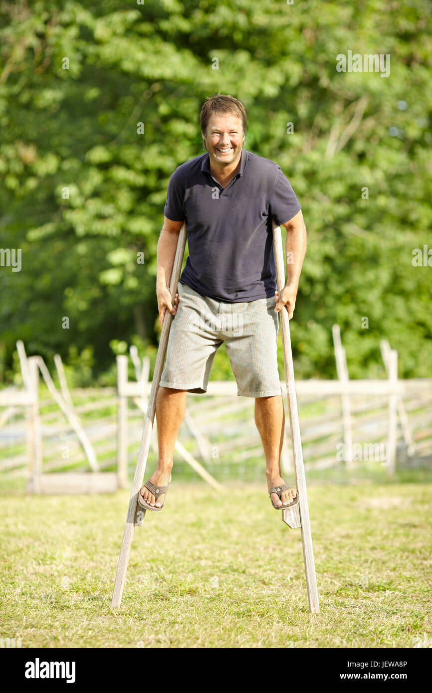 Smiling man walking on stilts Stock Photo Alamy