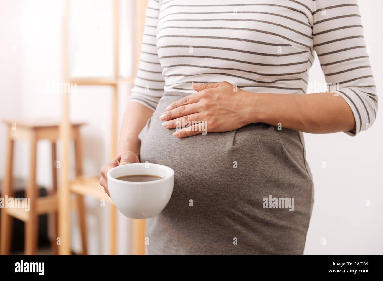 Plerasant pregnant woman holding a cup of coffee Stock Photo - Alamy