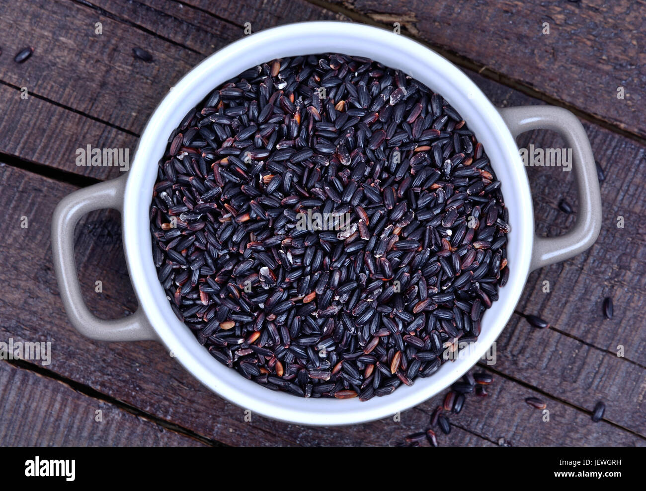 Black rice in a pot on wooden background Stock Photo