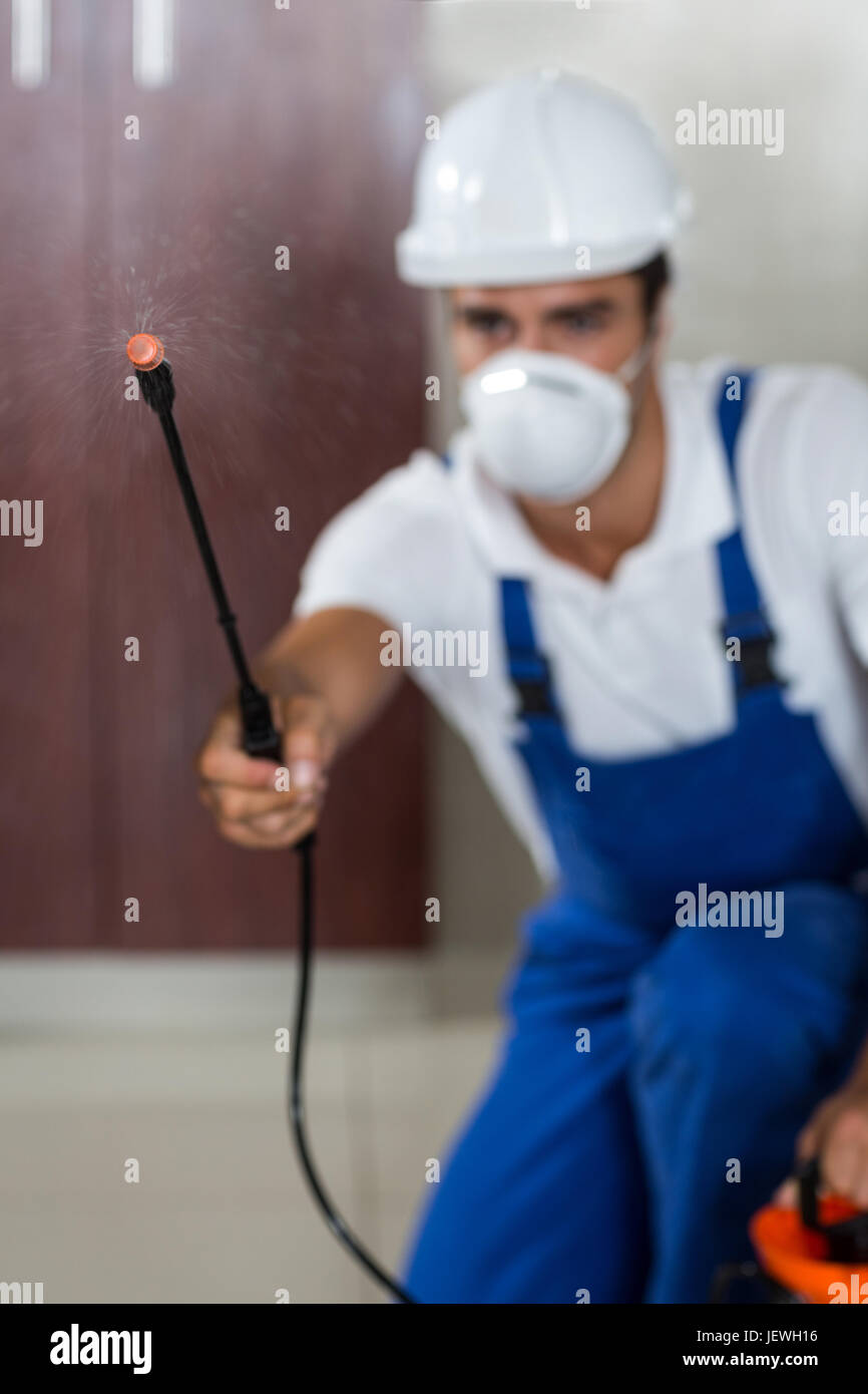 Manual worker spraying insecticide in kitchen Stock Photo