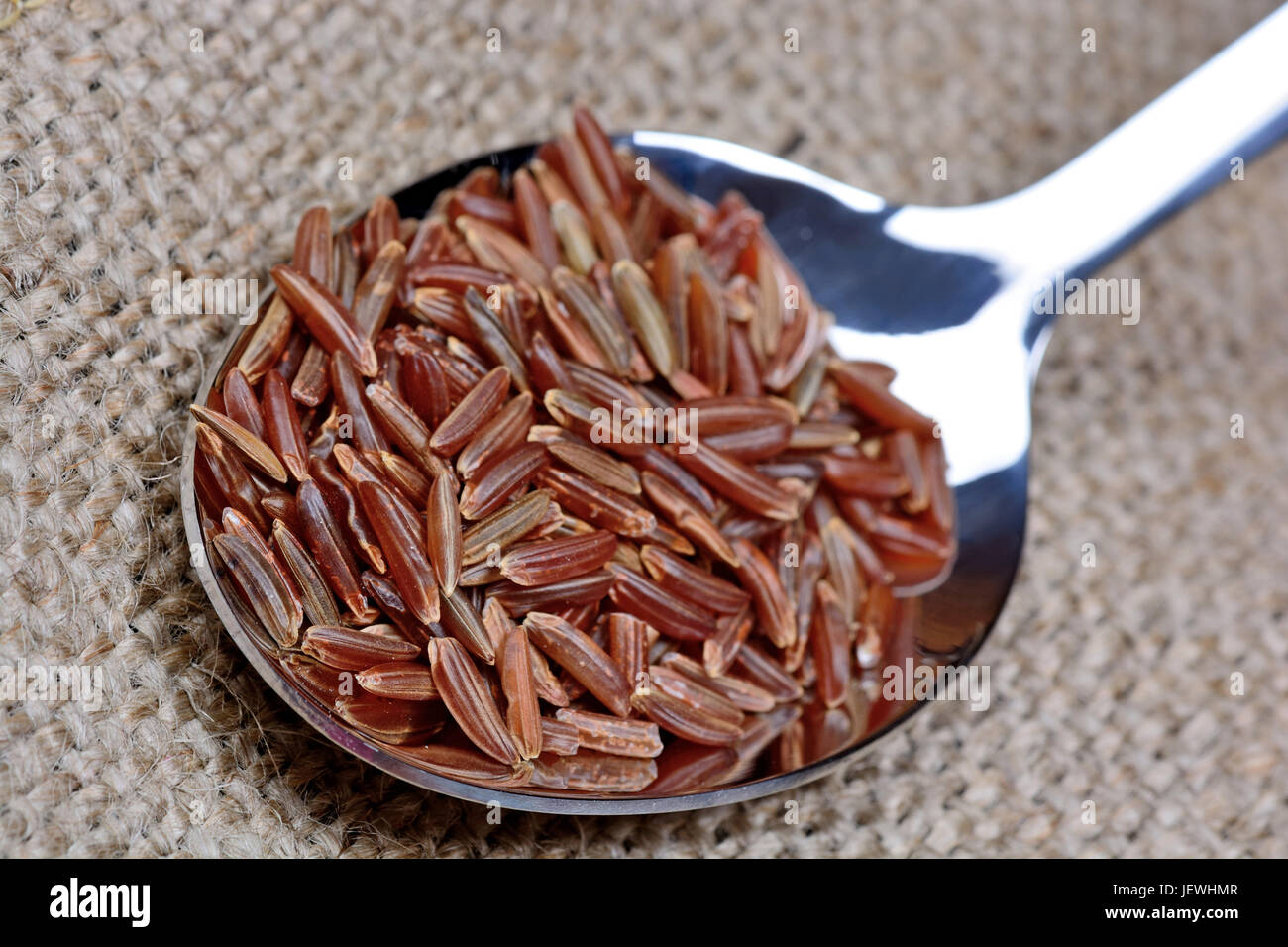Red rice in a spoon on table Stock Photo