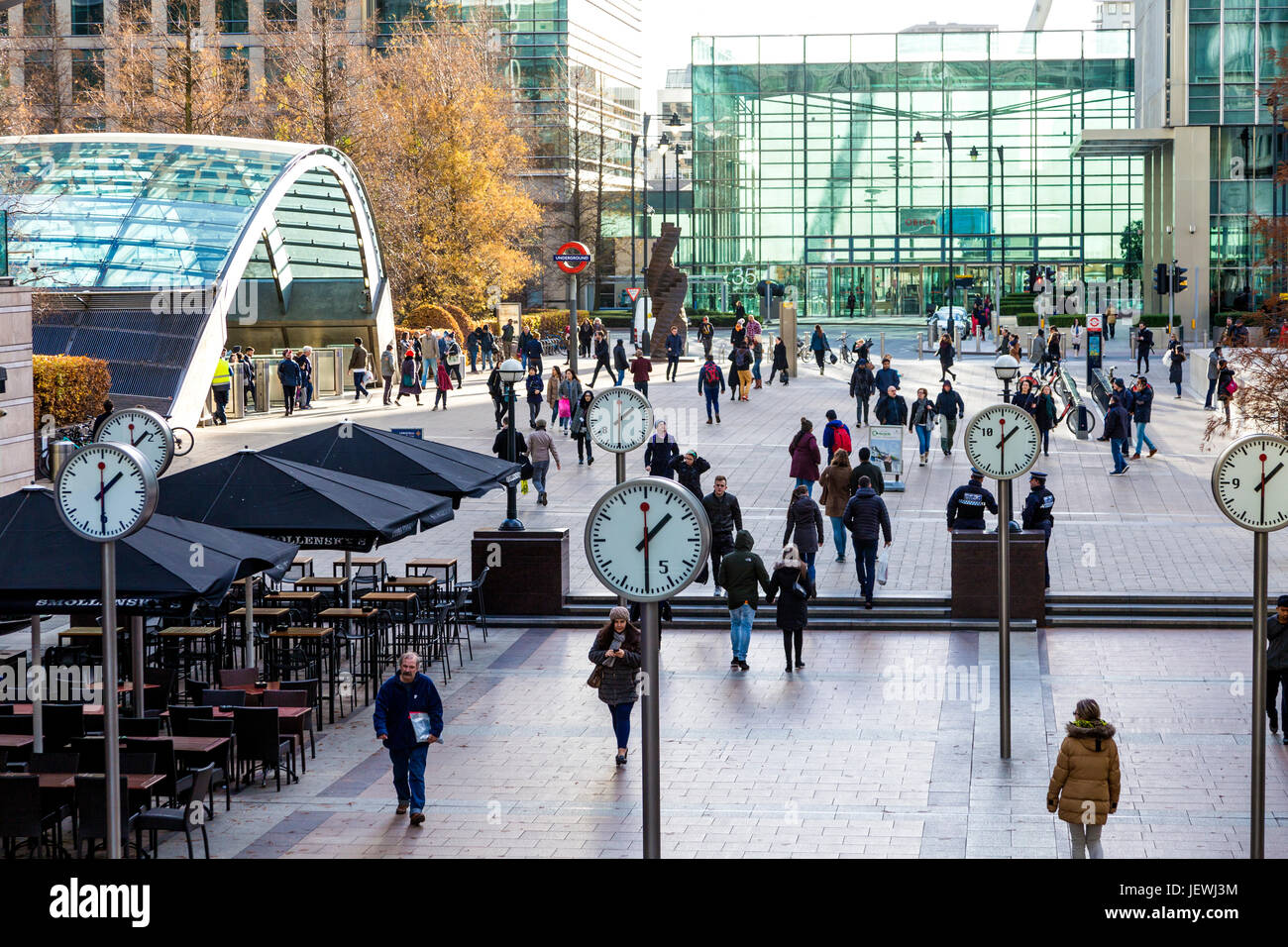 People walking in Reuters Plaza and Jubilee Plaza in Canary Wharf and public installation 'Six Public Clocks' by Konstantin Grcic, London, UK Stock Photo
