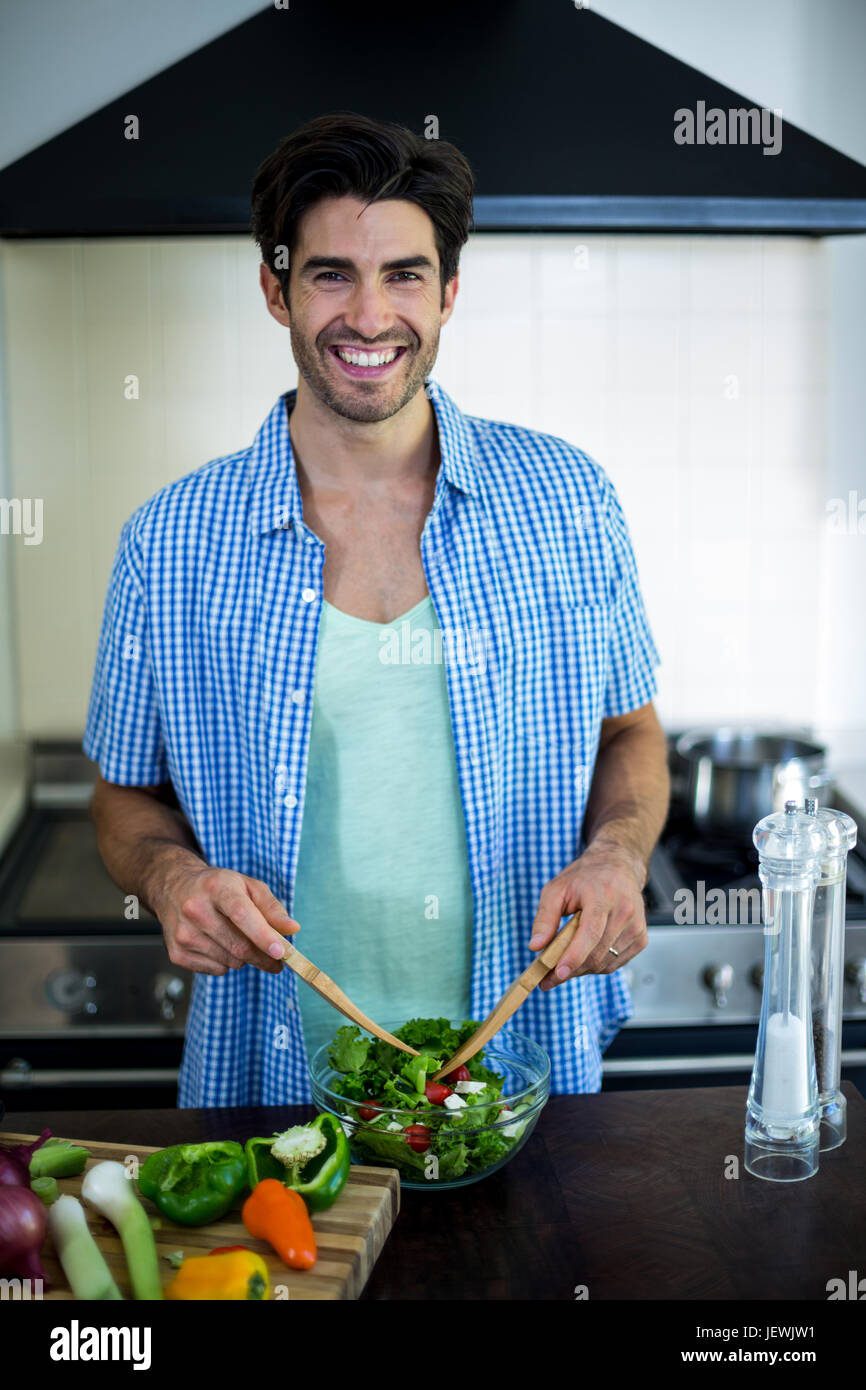 Portrait of man mixing a salad in kitchen Stock Photo