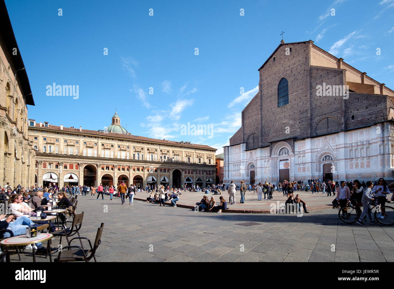 Bologna, Italy - April 17 2017: Citizens and tourists, on a sunny day, walk and relax in Piazza Maggiore, Bologna's main square, in front of the churc Stock Photo