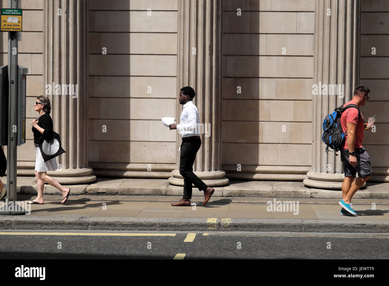 People walking along the street outside the Bank of England columns on Threadneedle Street in financial district City of  London UK  KATHY DEWITT Stock Photo