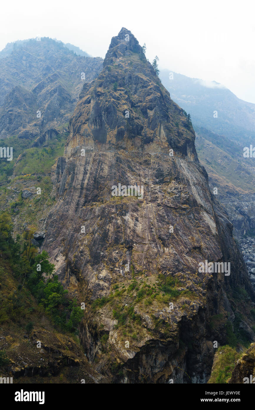 Rocky peak on the Annapurna Circuit between Chamje and Tal. A road carved in the rock face can be seen in the upper part of the peak Stock Photo