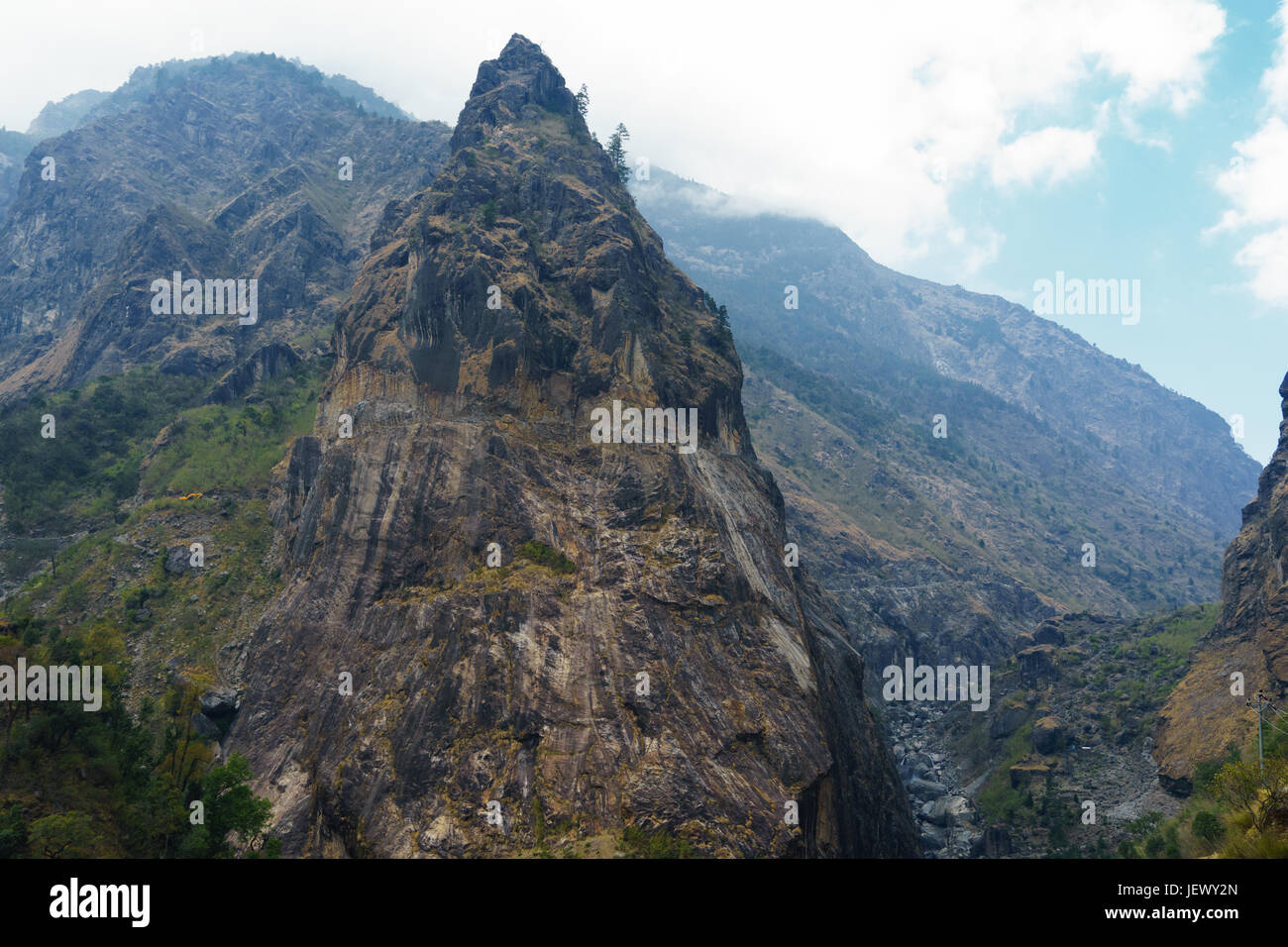 Rocky peak on the Annapurna Circuit between Chamje and Tal. A road carved in the rock face can be seen in the upper part of the peak. Stock Photo