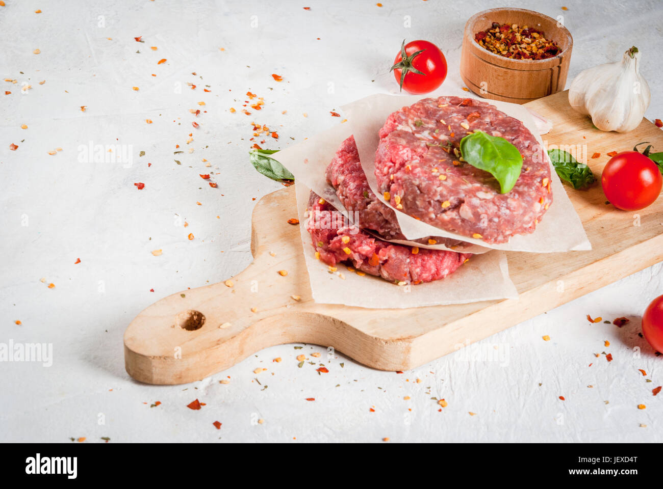 Fresh raw homemade minced beef steak burger with spices, tomatoes and