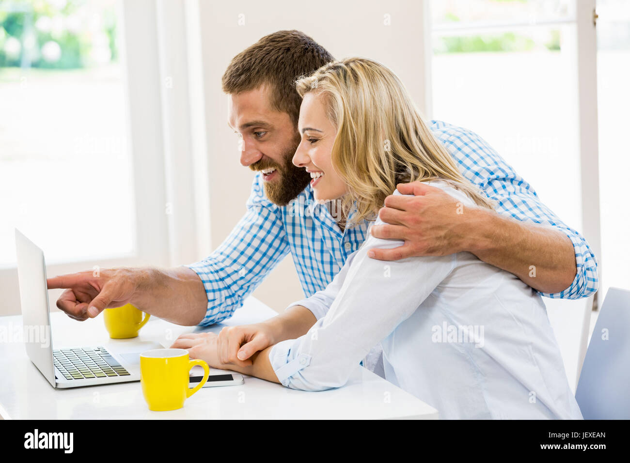 Happy young couple using laptop Stock Photo - Alamy