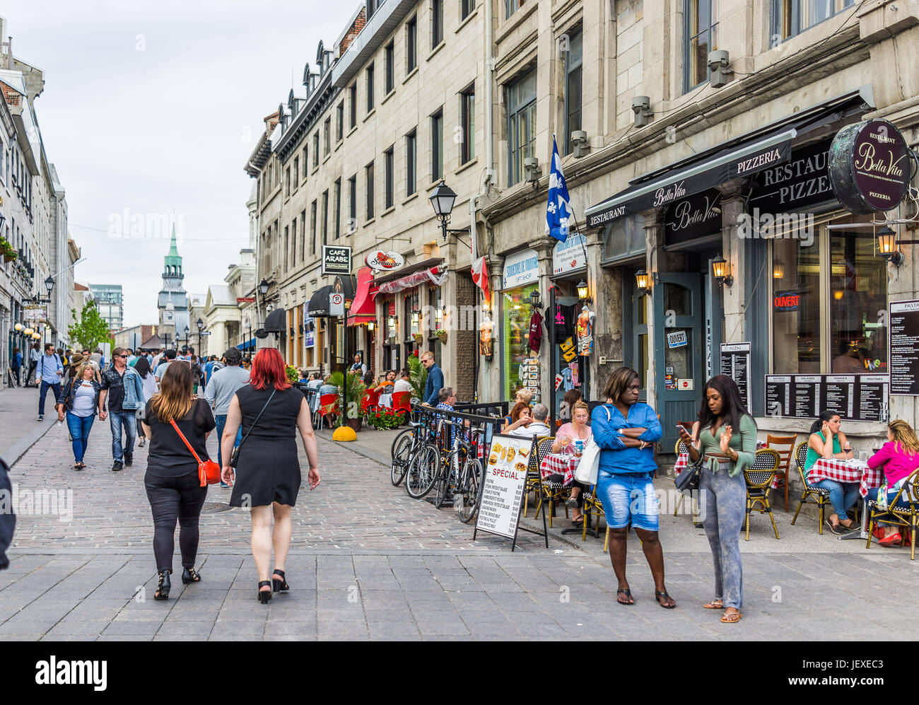 Montreal, Canada - May 27, 2017: Old town area with people walking up street in evening outside restaurants in Quebec region city Stock Photo