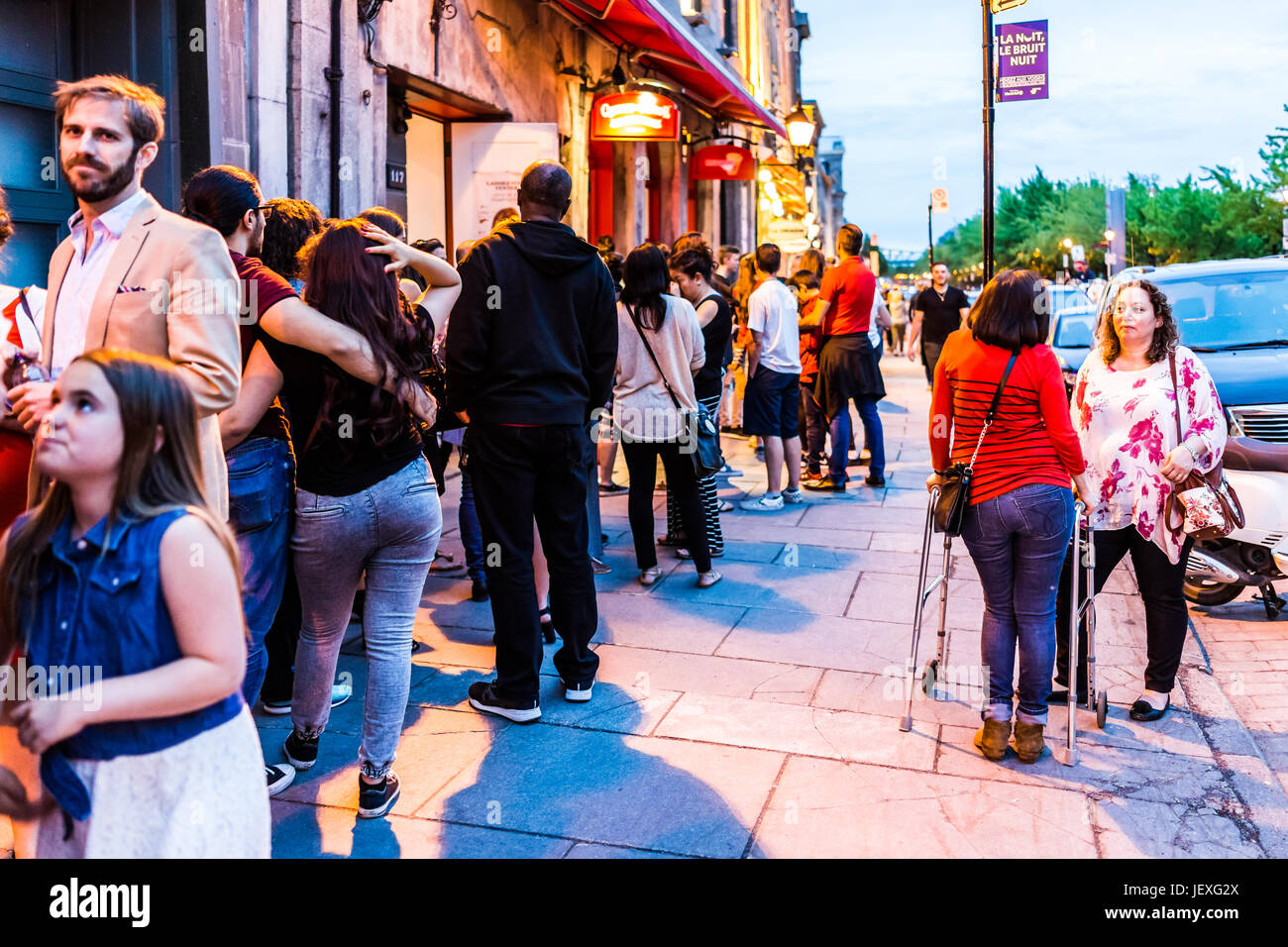 Montreal, Canada - May 27, 2017: Old town area with people waiting in line queue outside restaurant during evening night in Quebec region city Stock Photo