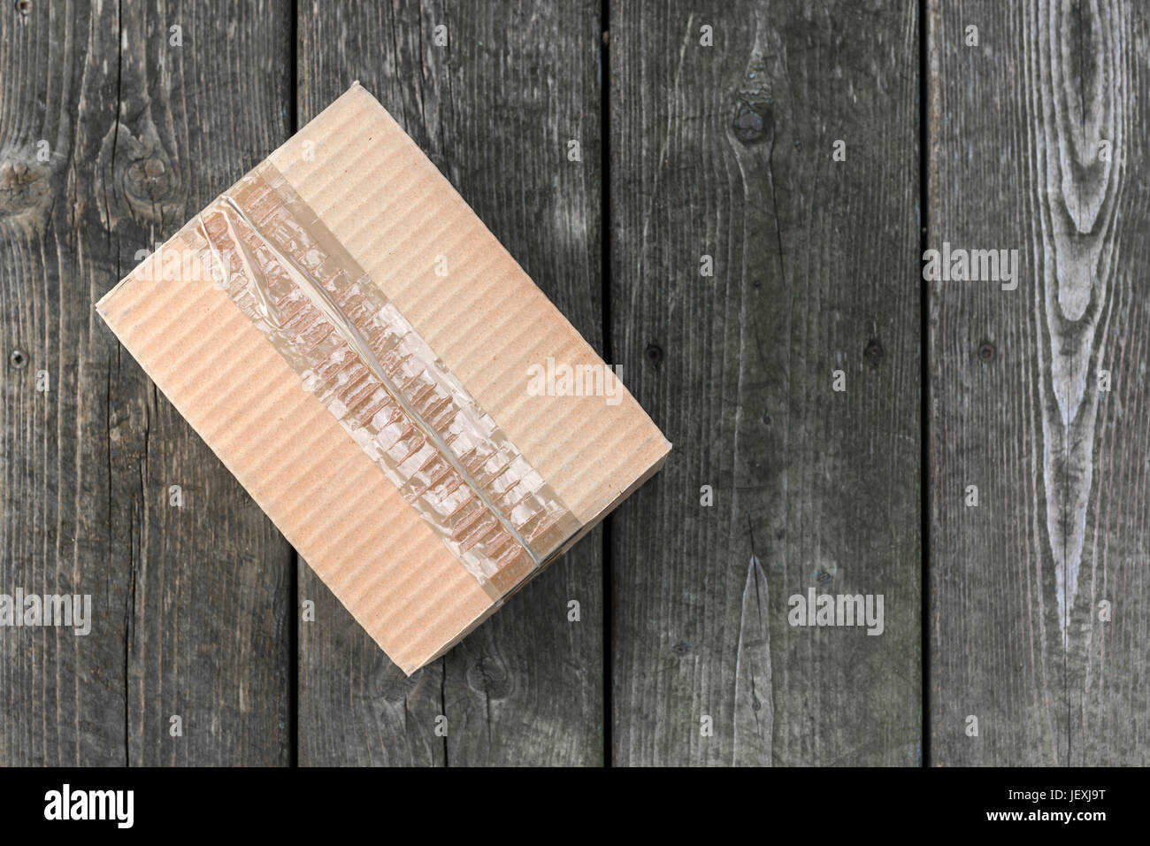 Cardboard delivery parcel box delivered to doorstep on old wood background, from above with copy space Stock Photo