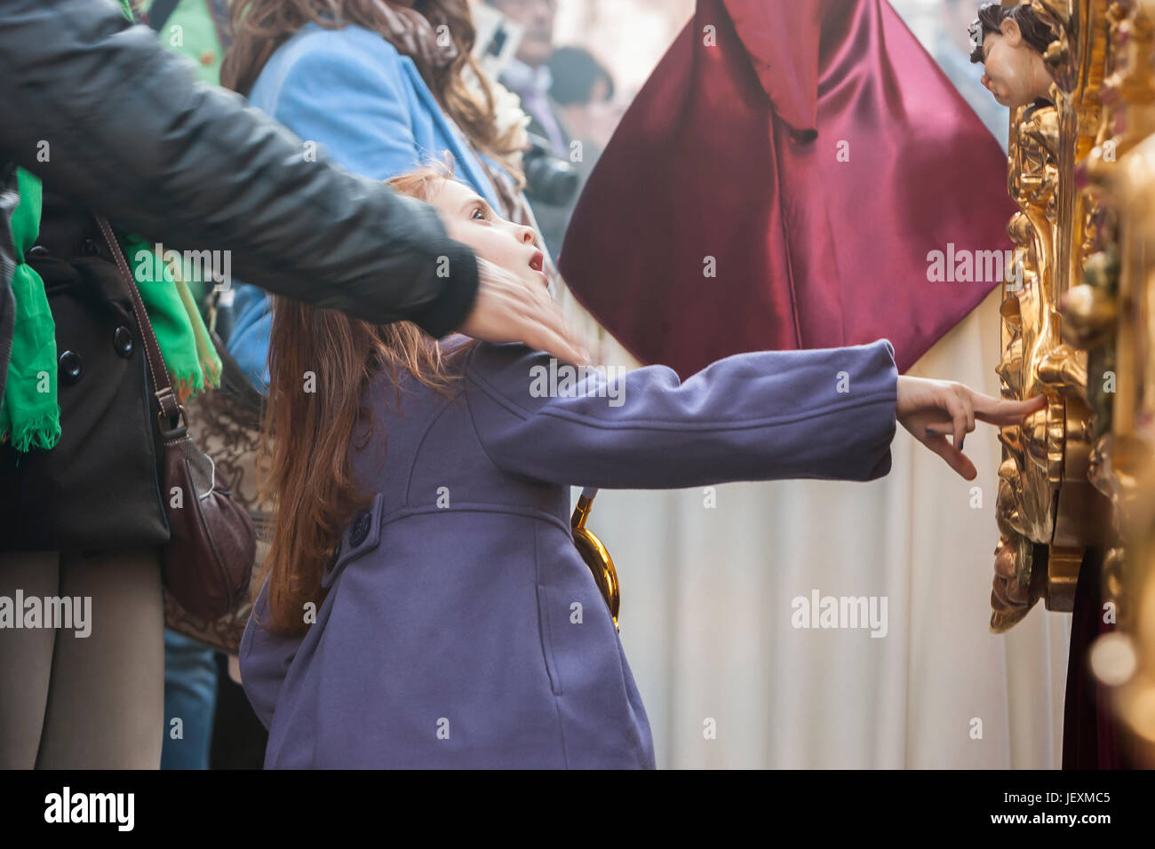 Linares, Jaen province, SPAIN - March 17, 2014: Girl tries to touch the skirt of the throne to have good luck, popular tradition in Andalusia, Easter  Stock Photo