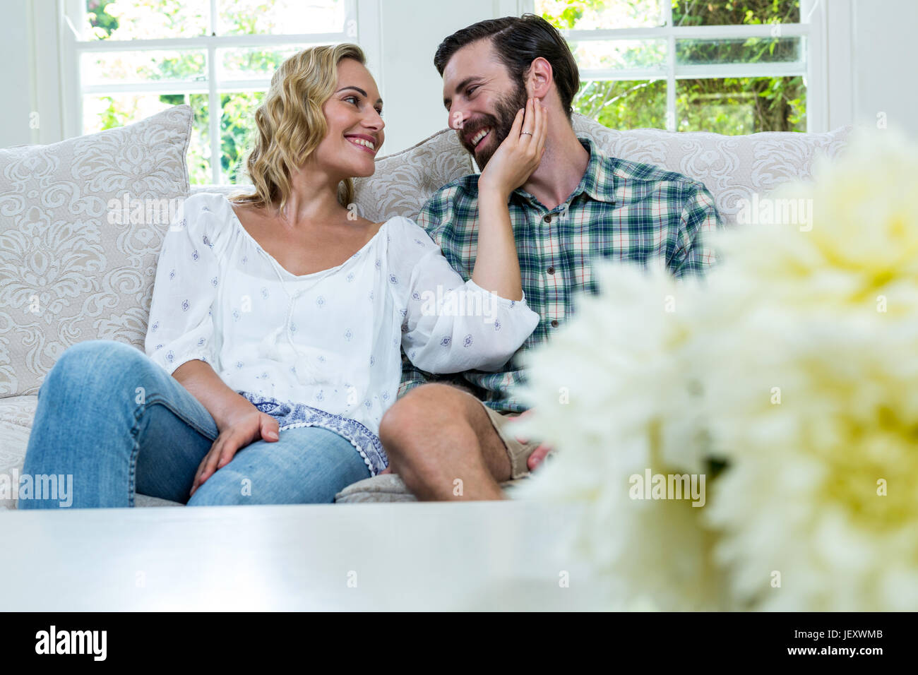 Romantic young couple sitting on sofa Stock Photo - Alamy