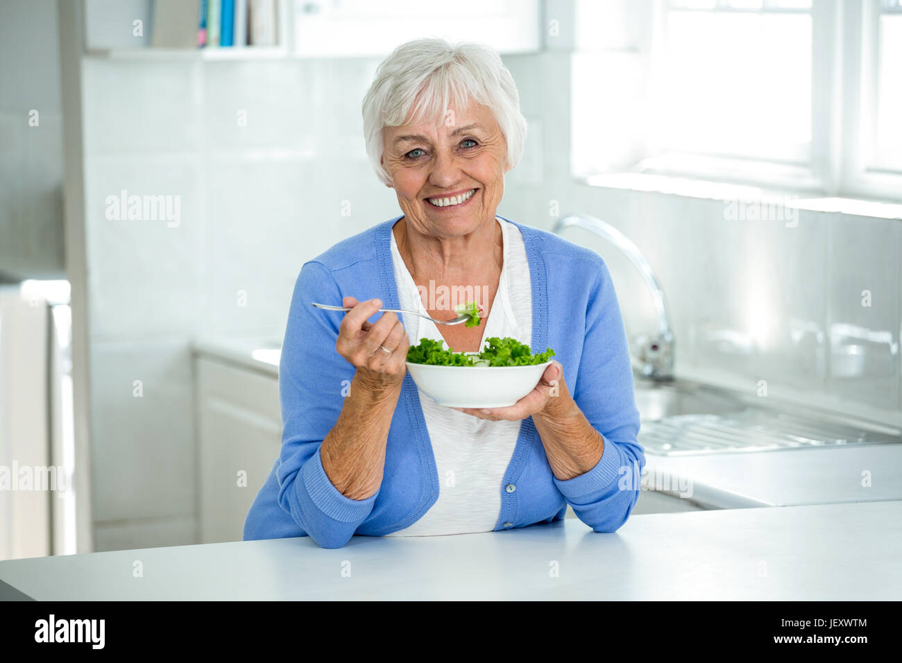 Happy senior woman with salad in kitchen Stock Photo
