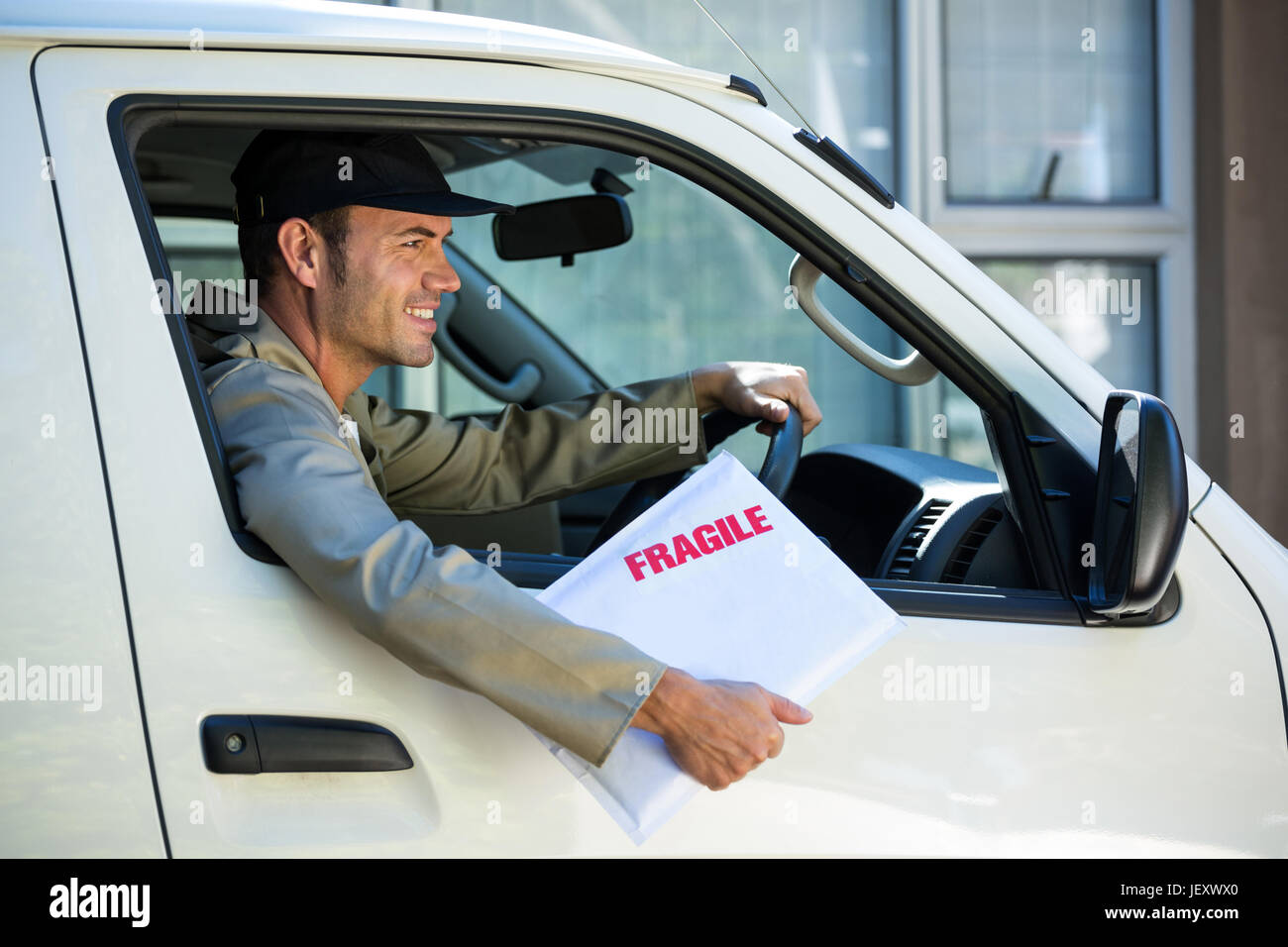 Smiling delivery man sitting in his van Stock Photo - Alamy