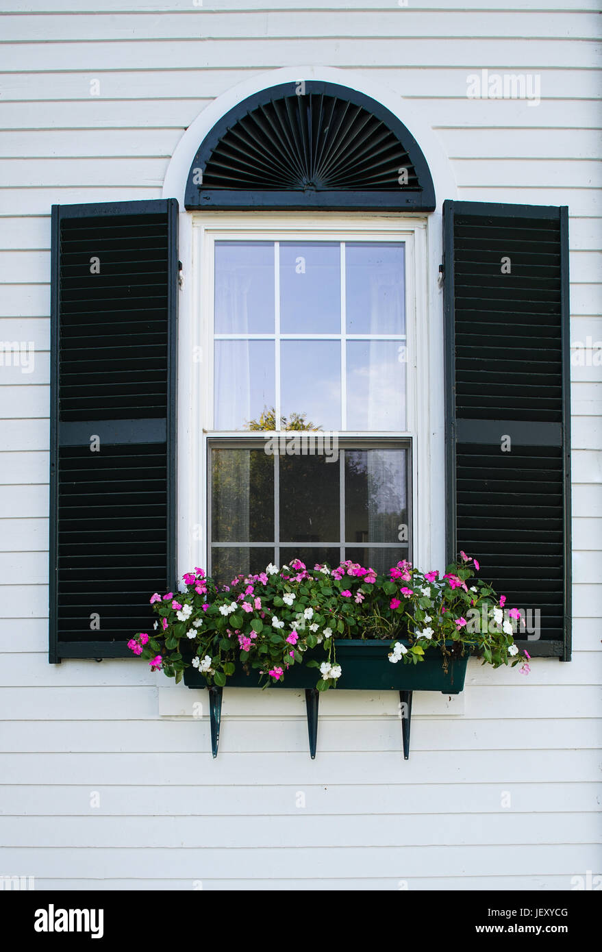 New England window with black shutters and flower box. Stock Photo
