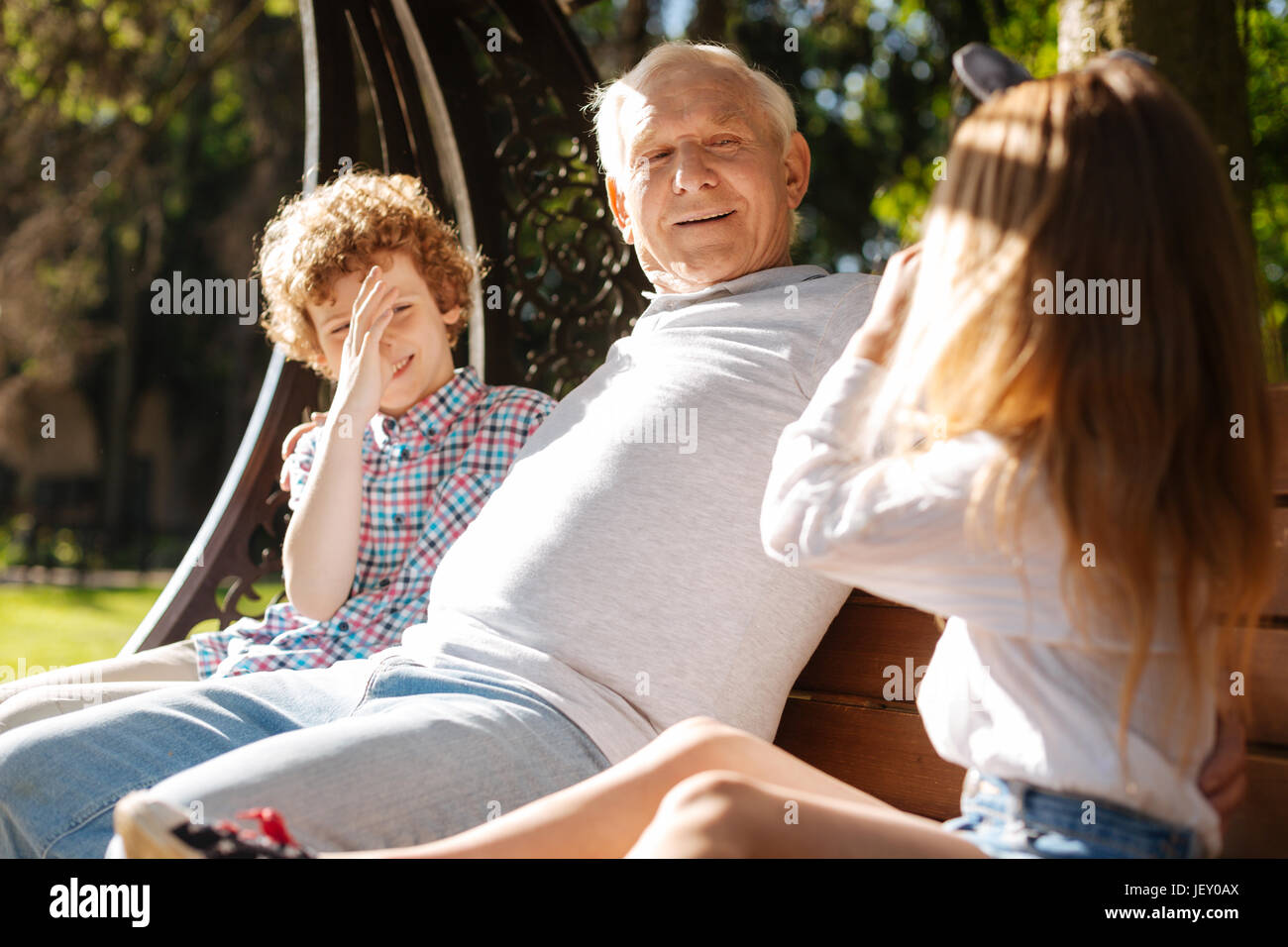 Funny children making faces while being near their grandpa Stock Photo