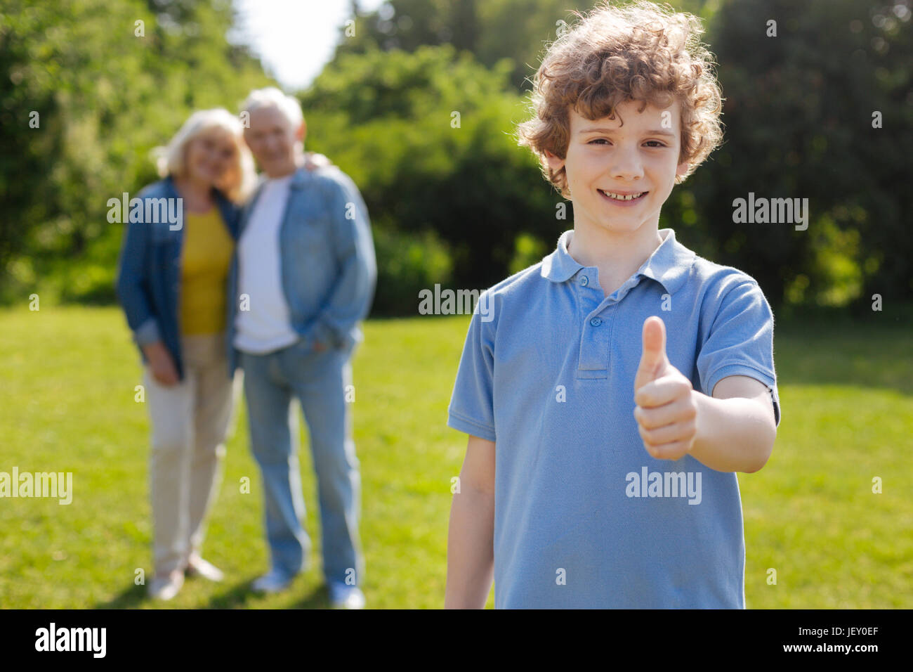 Positive delighted boy with curly hair standing on the foreground Stock ...