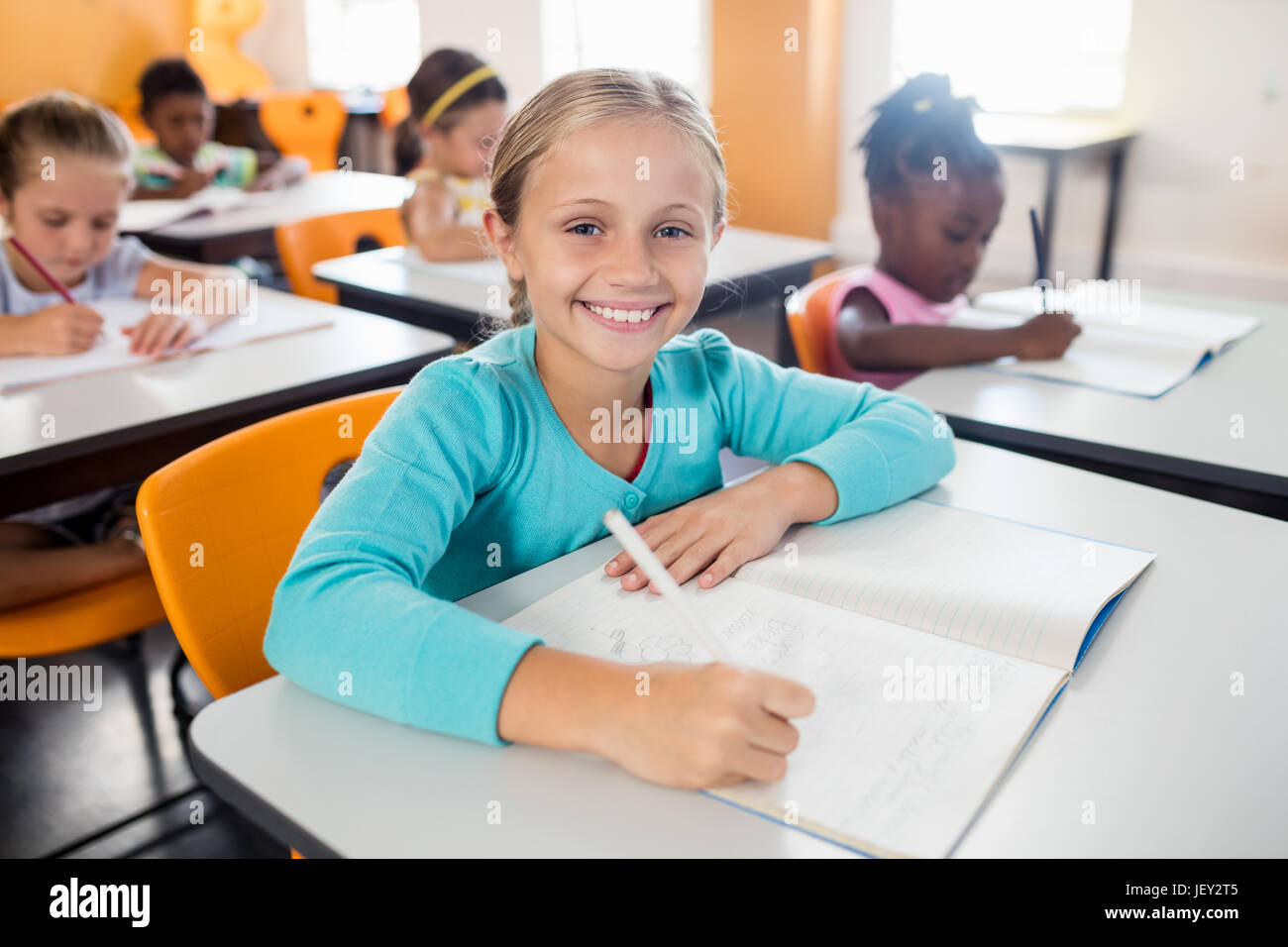 Portrait of smiling pupil sitting at desk Stock Photo - Alamy
