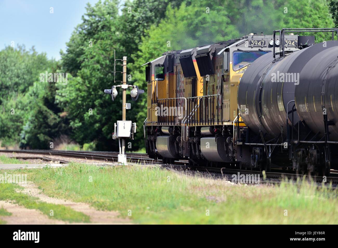 Two locomotive units lead an eastbound Union Pacific feight train with a mixed consist of freight through a grade crossing. Stock Photo