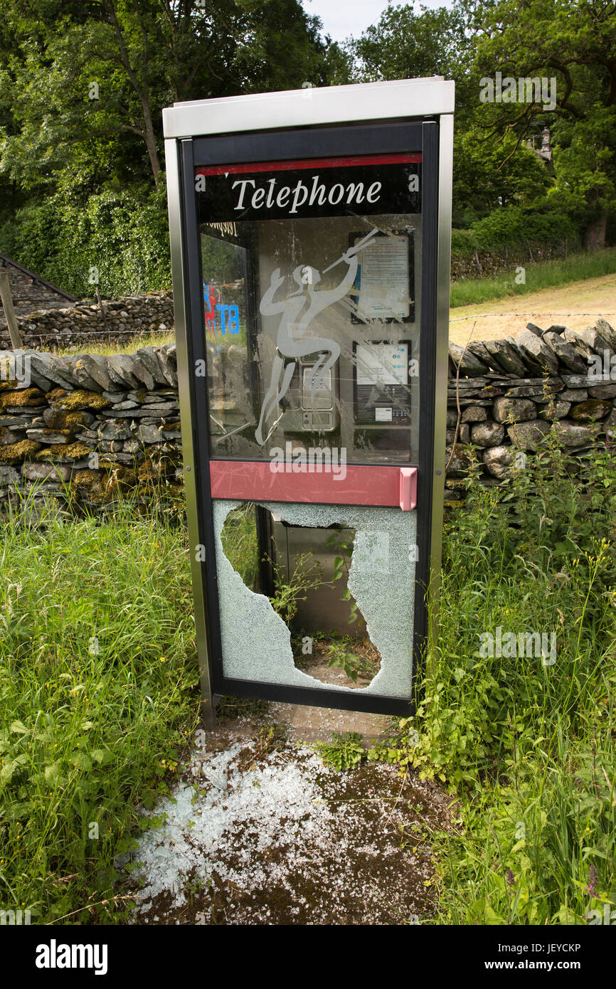 UK, Cumbria, Skelwith Bridge, vandalised country village phone box with smashed glass door panel Stock Photo