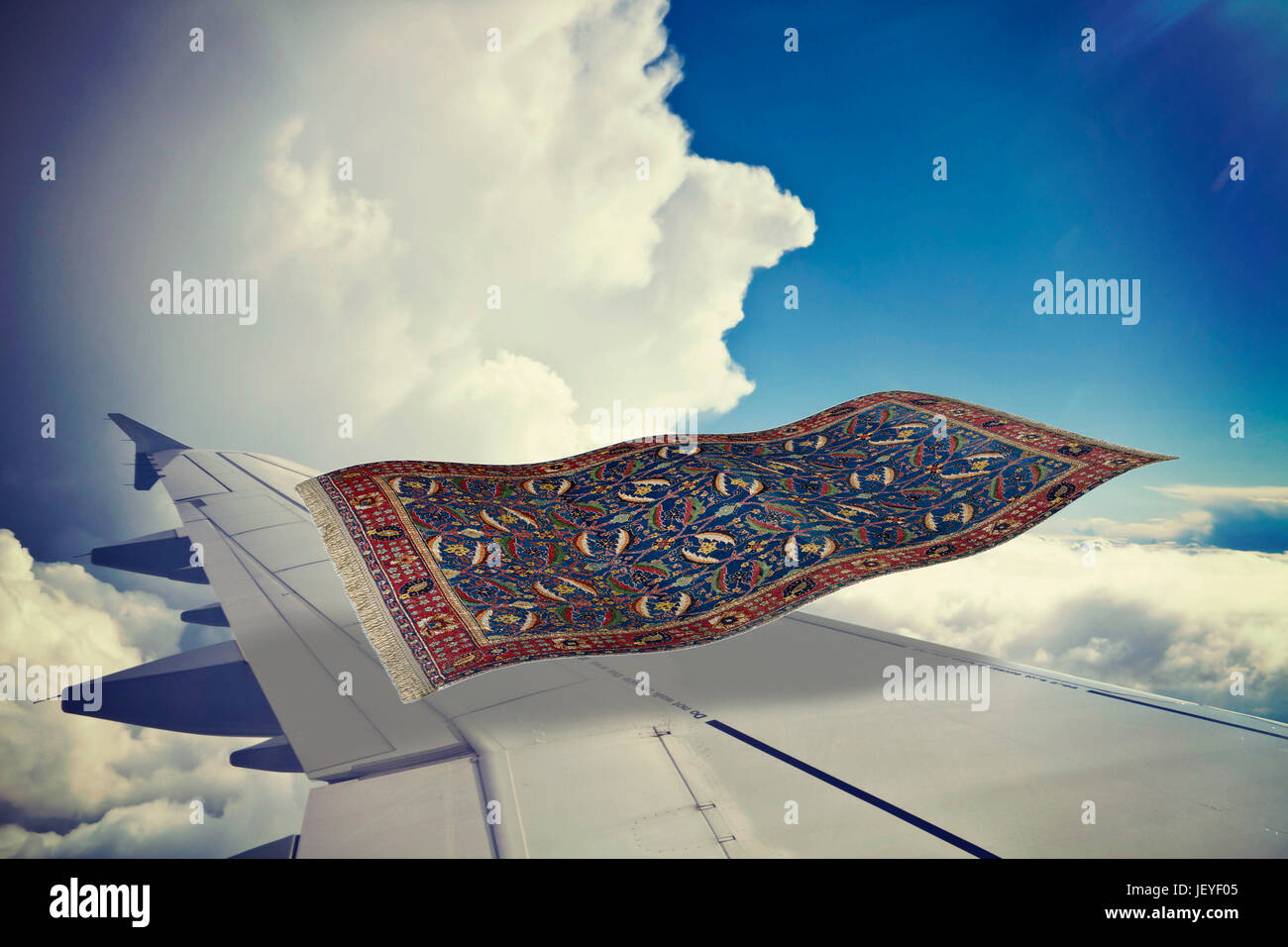 surrealistic flying carpet flies over an airplane in the blue sky. Partial 3D rendering Stock Photo