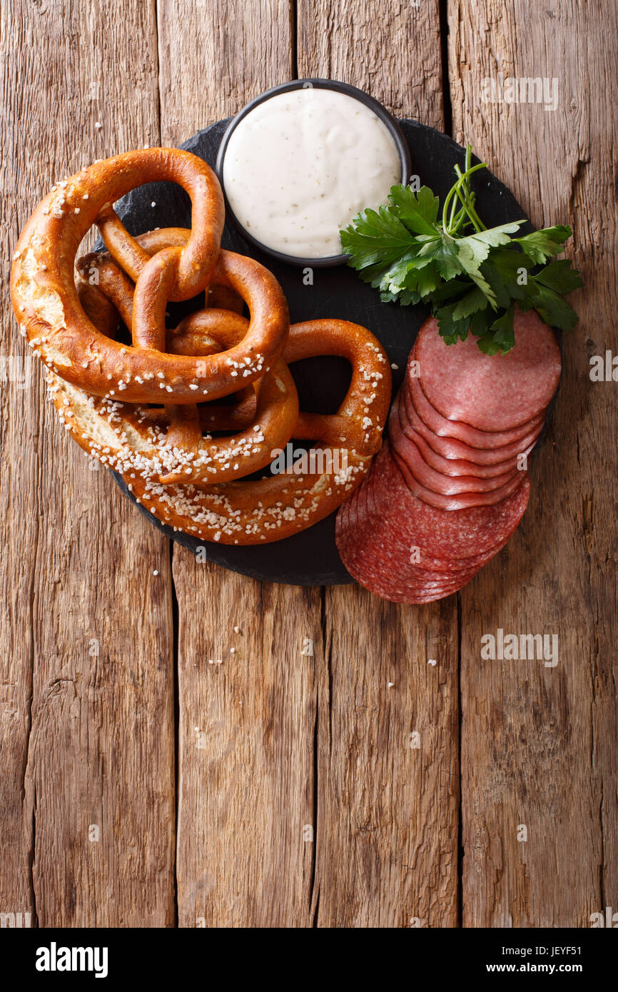 German appetizer sliced salami and pretzels with sauce closeup on the table. vertical view