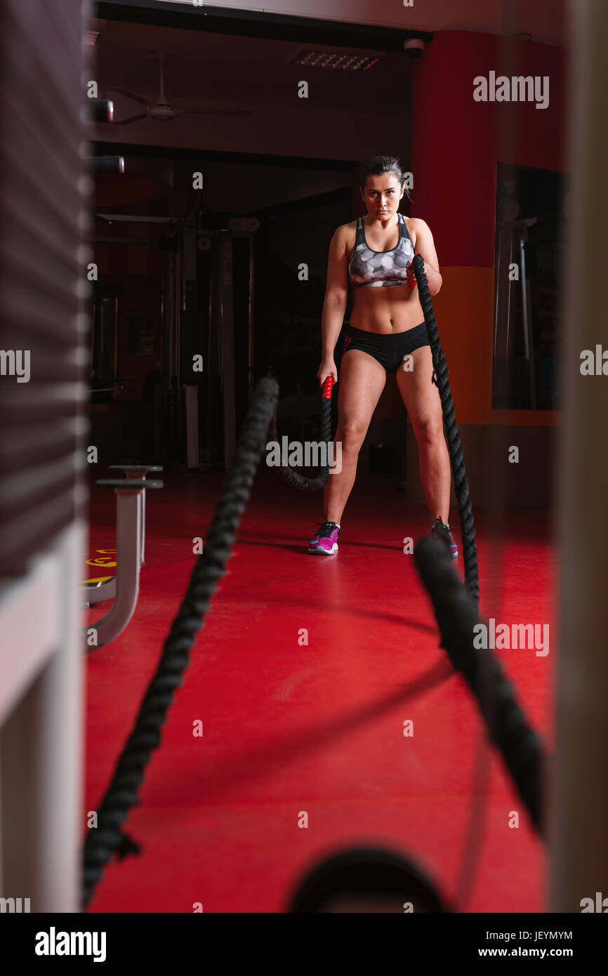 Crossfit battling ropes at gym workout fitness exercise. Woman ...