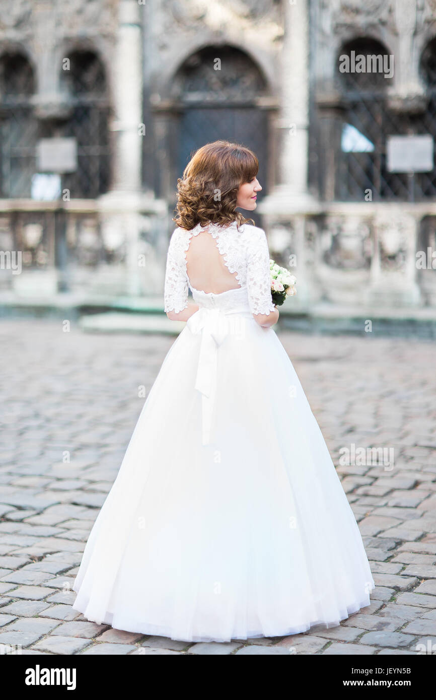 The back view of the bride with the wedding bouquet in the street Stock ...