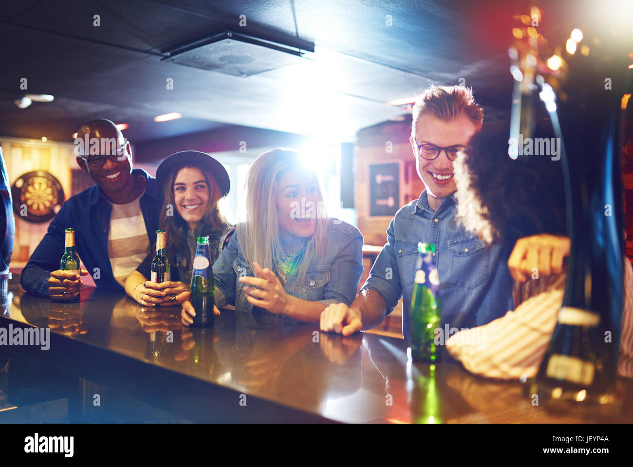 Horizontal indoors shot of young cheerful friends talking in the bar. Friends and fun concept. Stock Photo