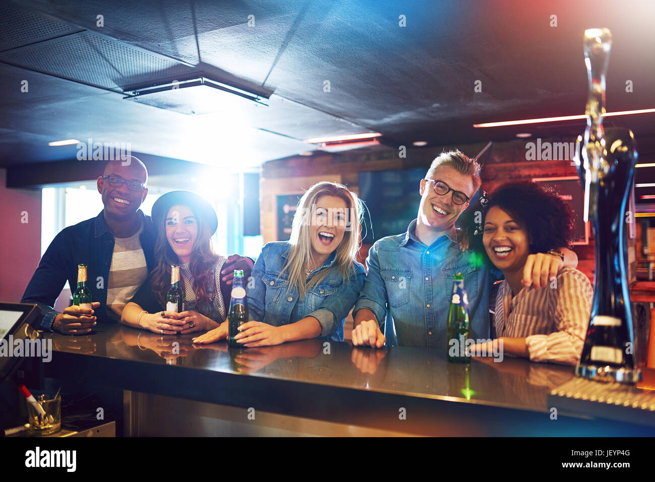Joyful friends laughing and looking at camera while drinking inside the bar. Stock Photo
