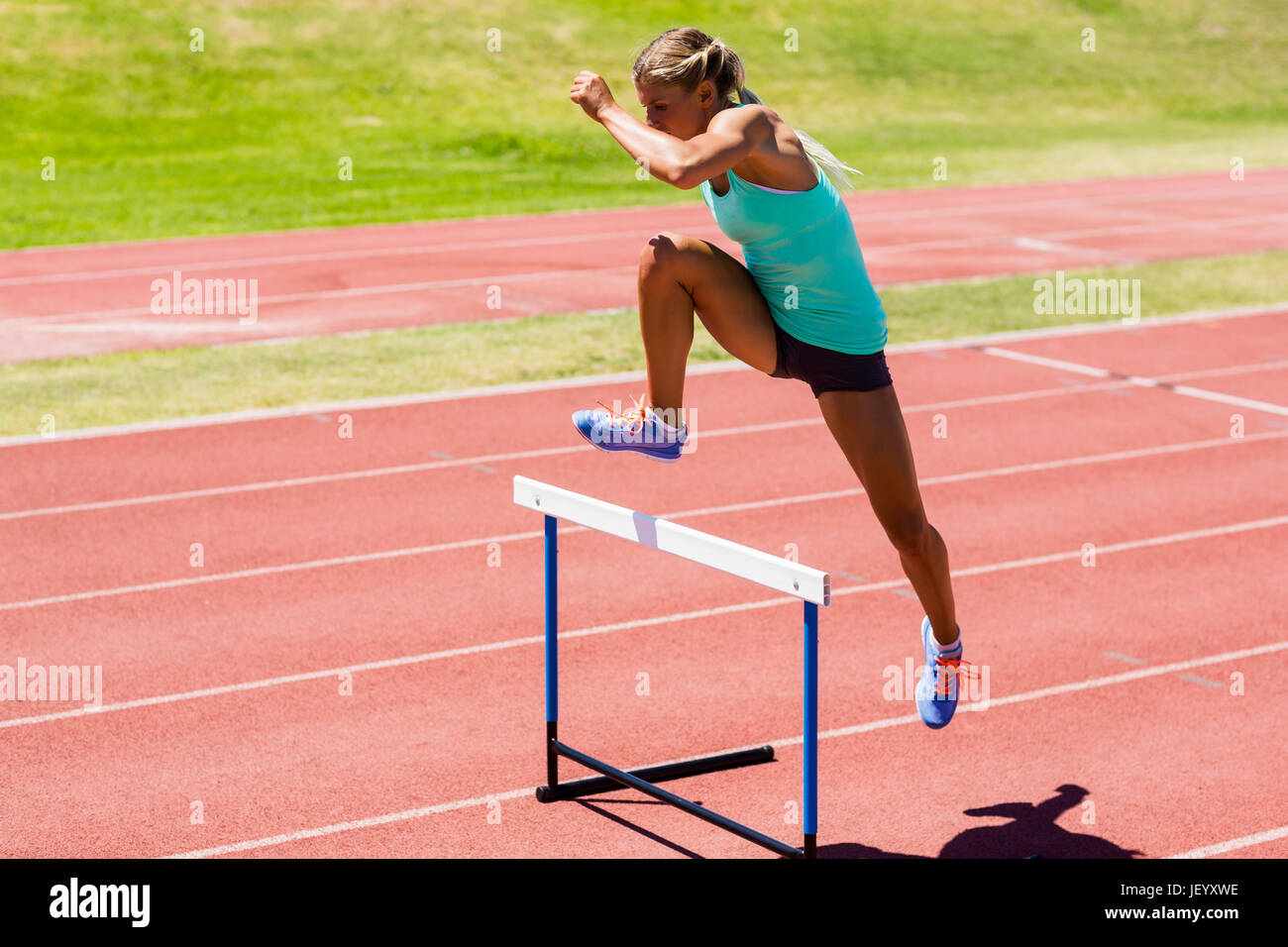 Female athlete jumping above the hurdle Stock Photo