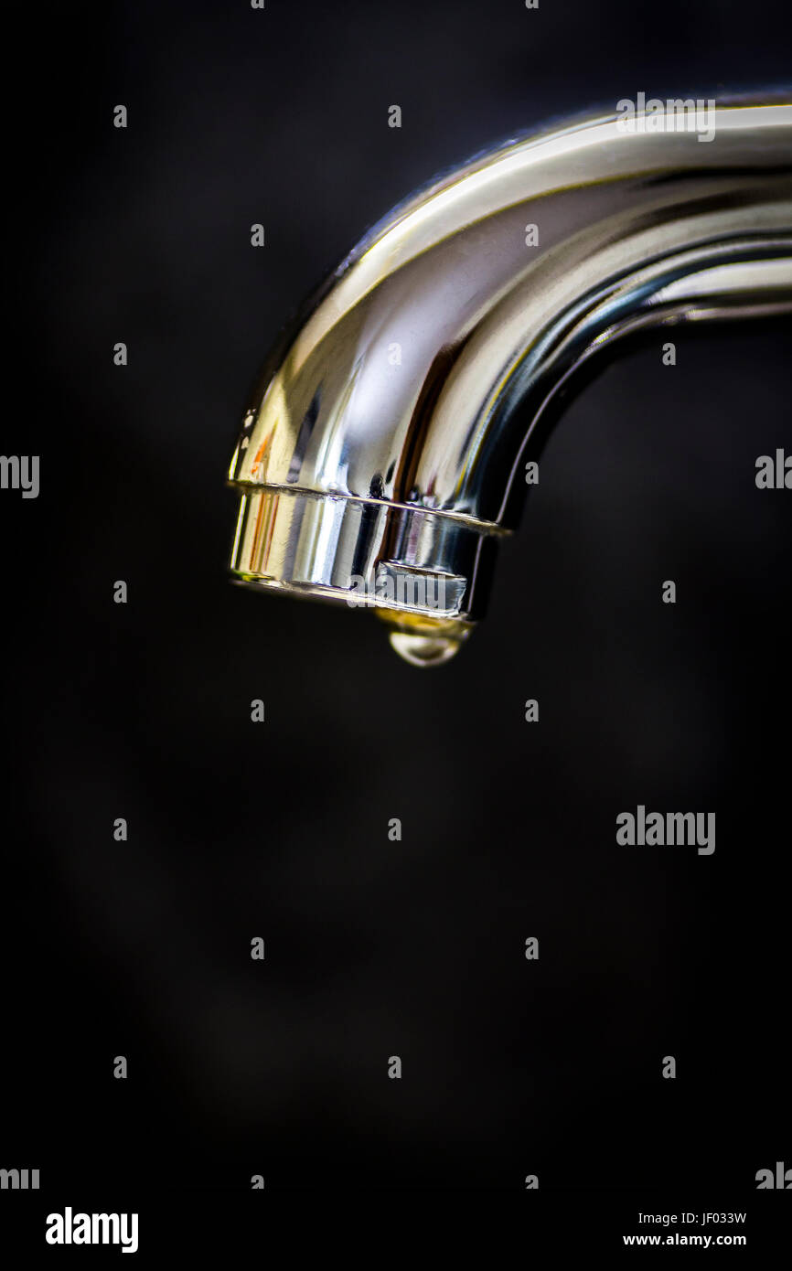 A Drop Of Water From The Faucet Close Up On A Black Background