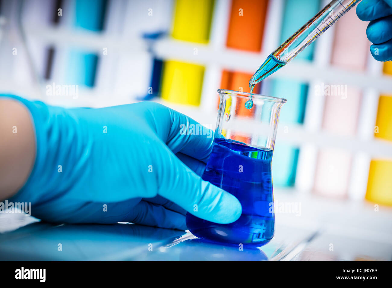 Scientist takes sample of chemical liquid with a pipette. Laboratory