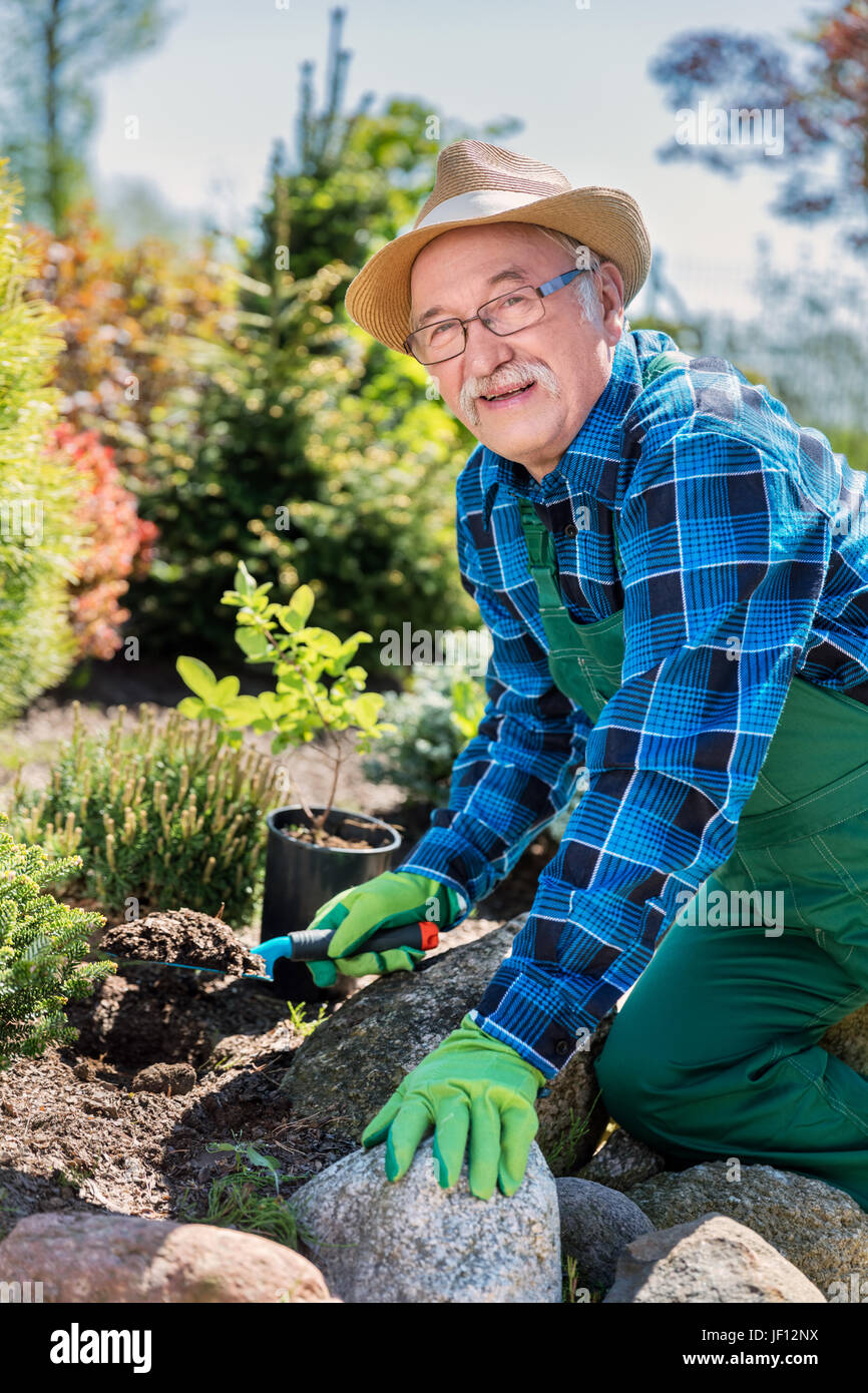 Senior gardener digging in a garden. Preparing soil for a new plant. Gardening concept. Stock Photo