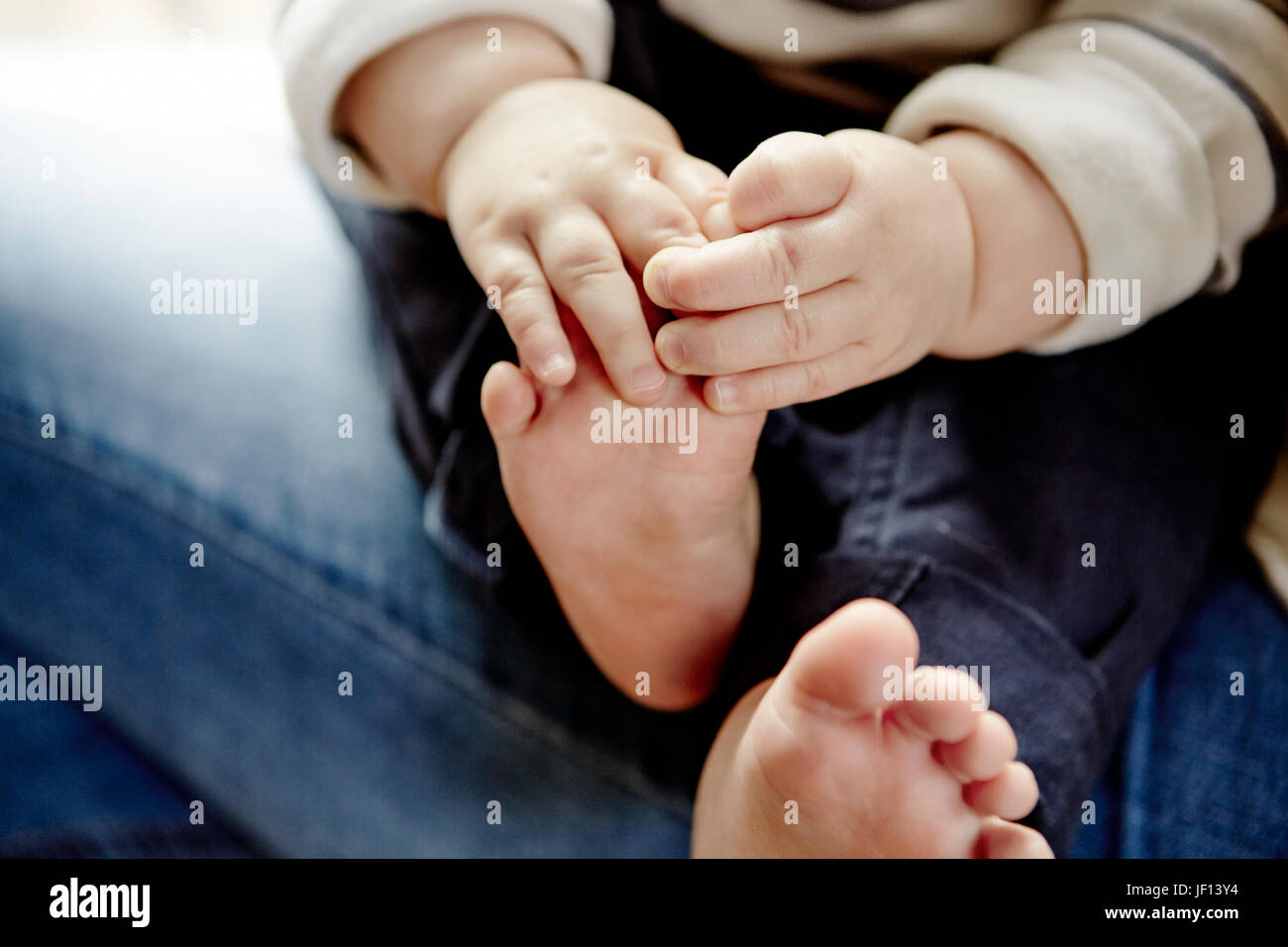 Babys hands holding feet Stock Photo - Alamy