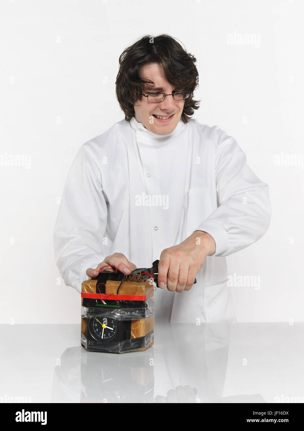 A young man painfully defuses a bomb cutting through the red wire Stock Photo