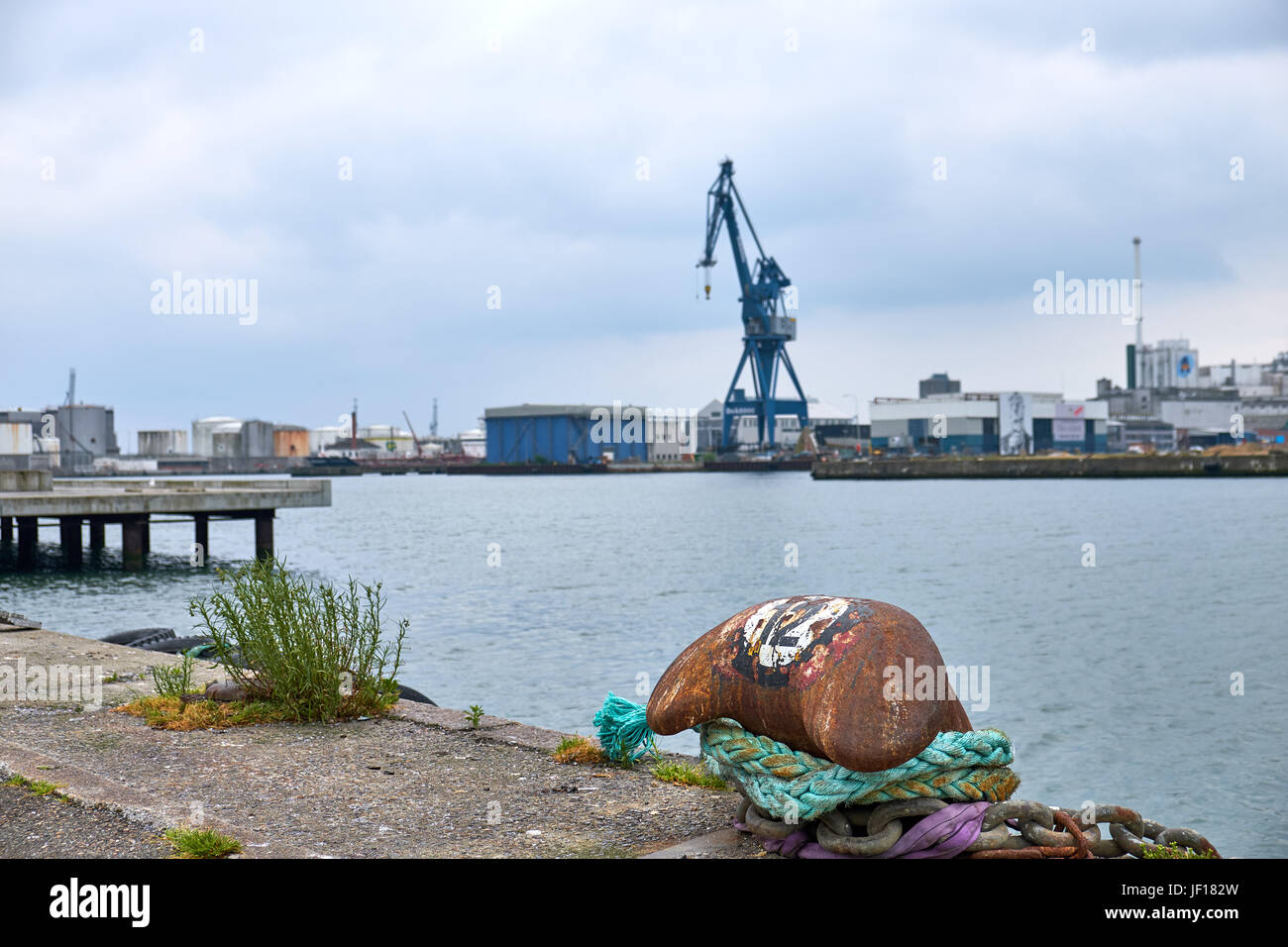 Mooring post on the quay of Aarhus in Denmark, with a gantry crane and warehouses in the background Stock Photo