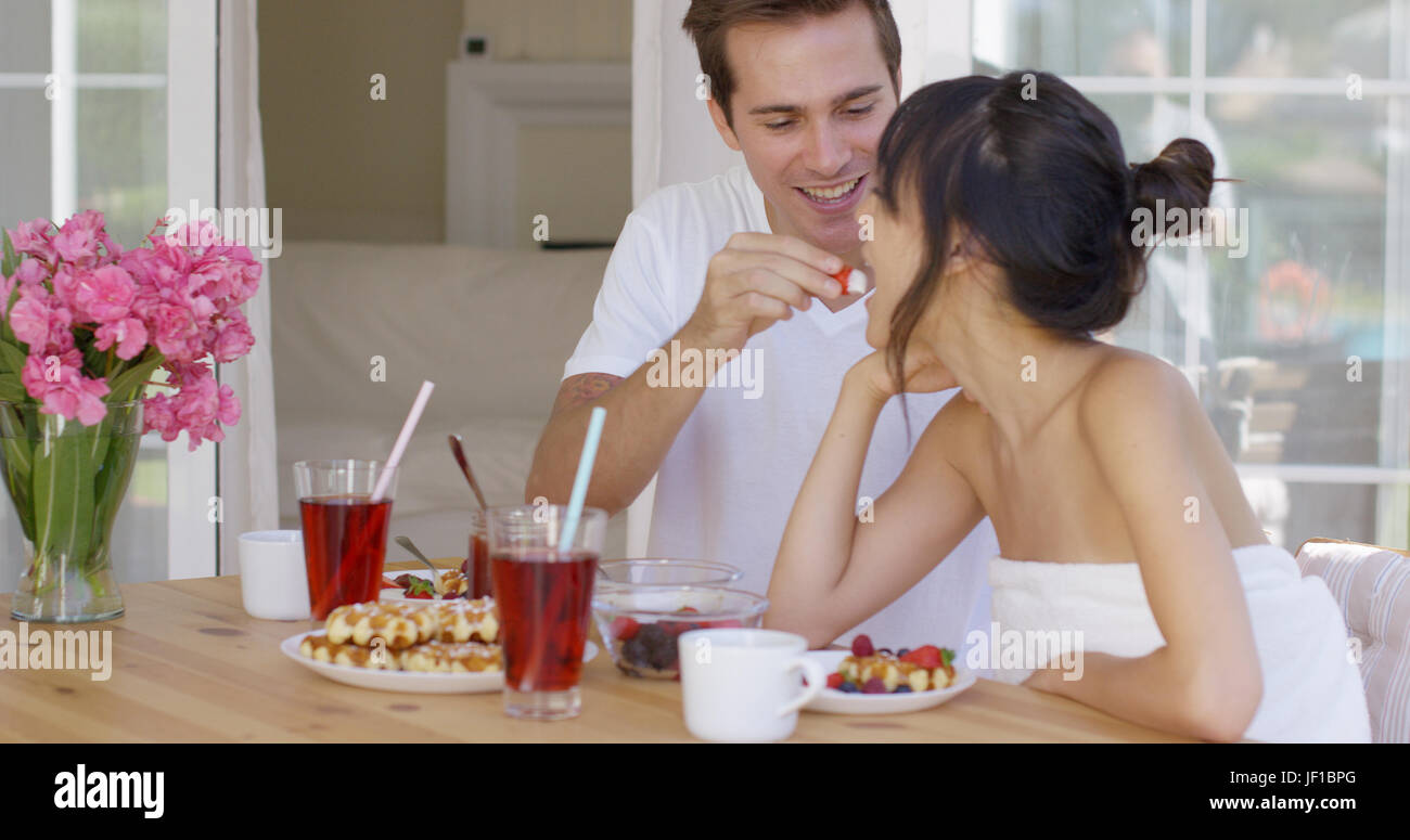 Man feeding his wife fruit at breakfast Stock Photo