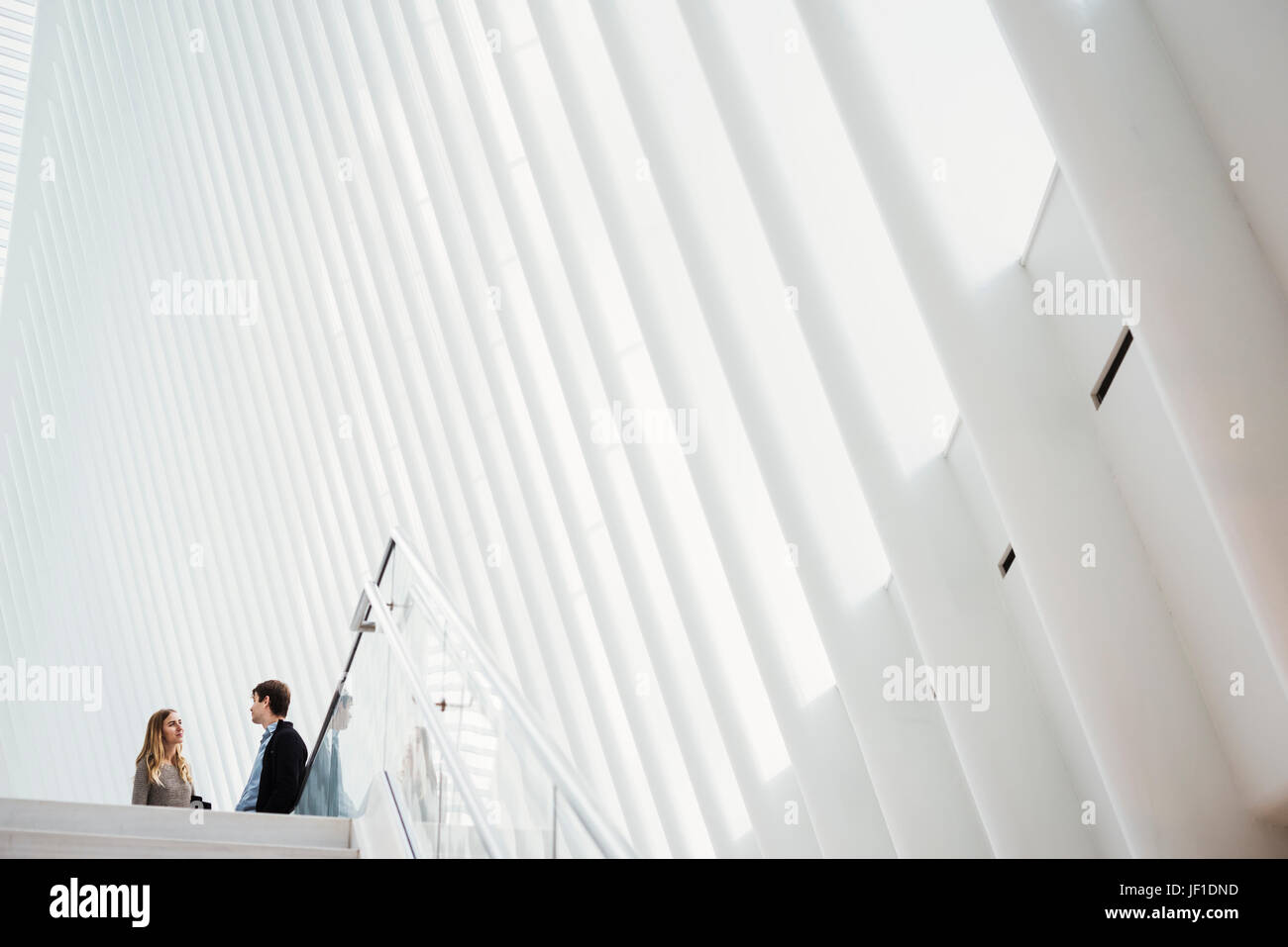 Two people at the top of steps in the central atrium of the Oculus building, talking. Stock Photo