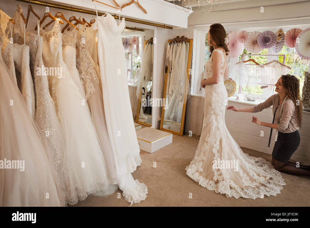 Rows of wedding dresses on display. A young woman in a full length