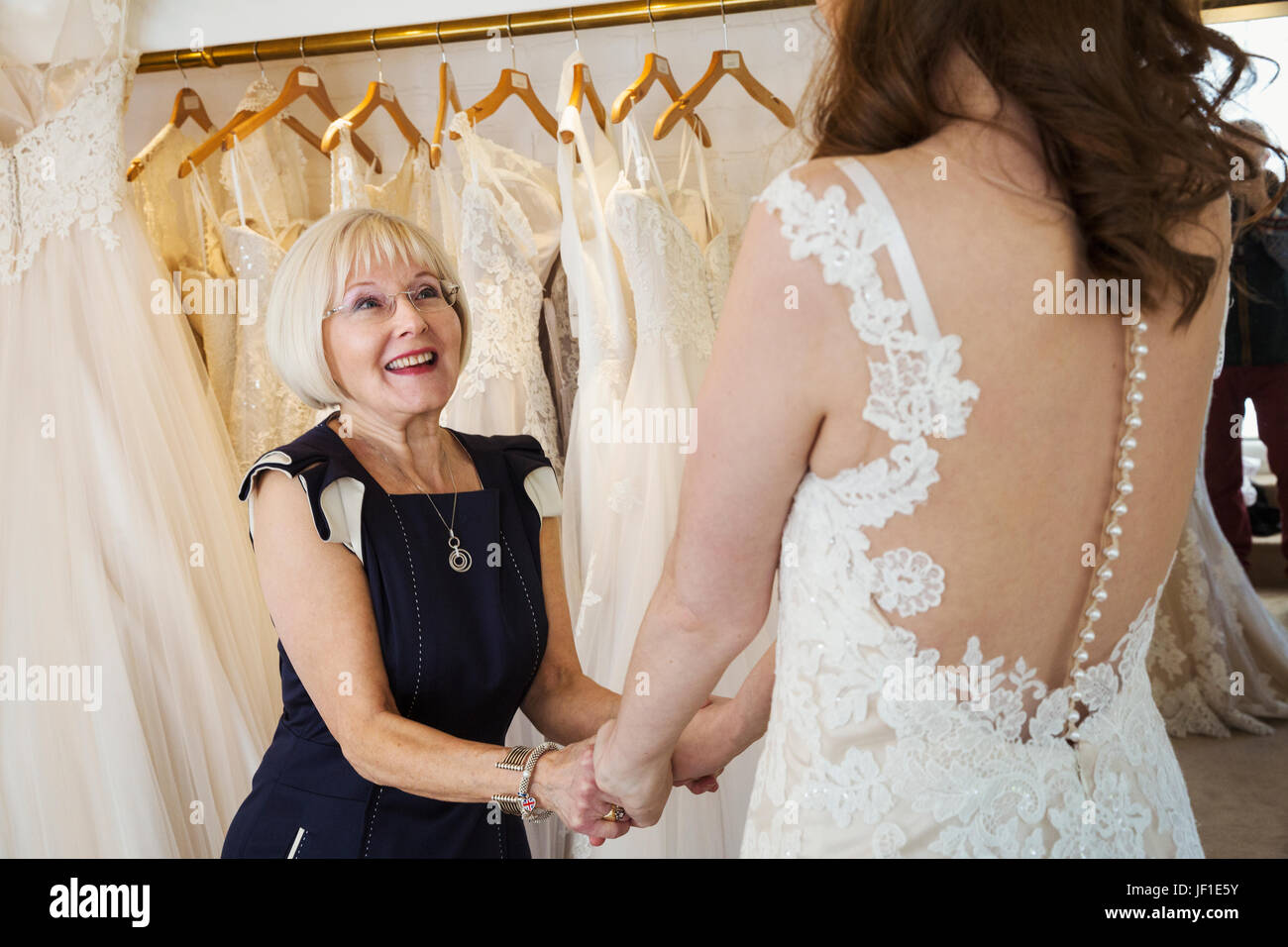 A Woman A Bride To Be Trying On Dresses With The Help Of A Sales Assistant In A Wedding Dress 8259
